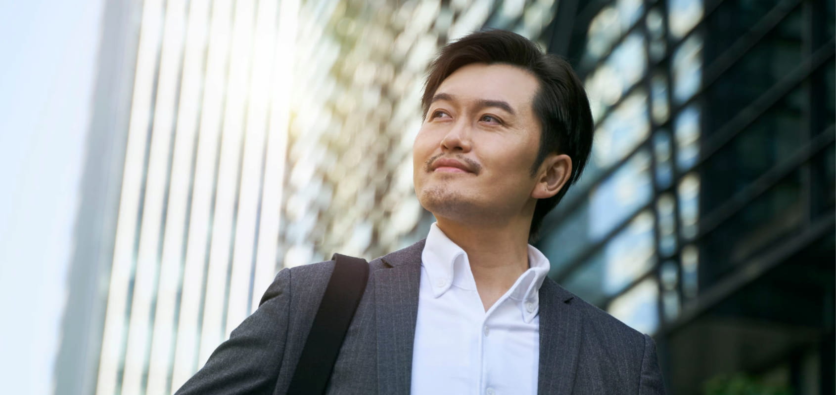 Asian businessman with a smile on his face as he walks to a destination